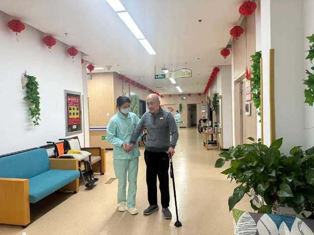 護(hù)理員喬瑞霞正在輔助入住中心的全托老人行走.jpg